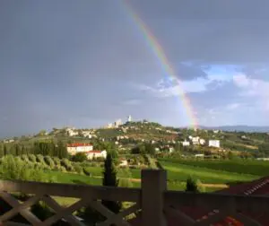 A rainbow over the hills and houses of a village.